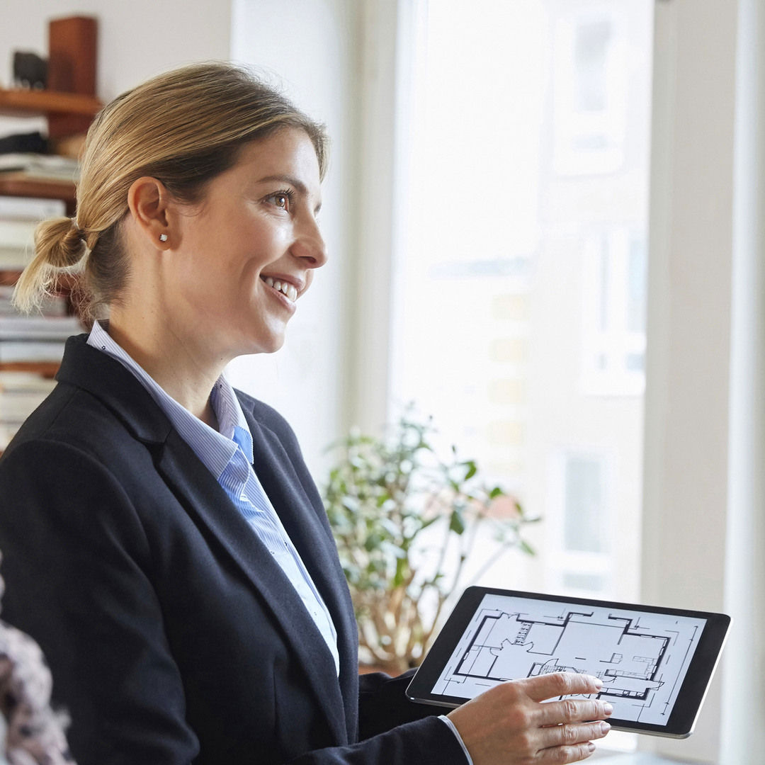 Mäklare som visar en planlösning på en ipad