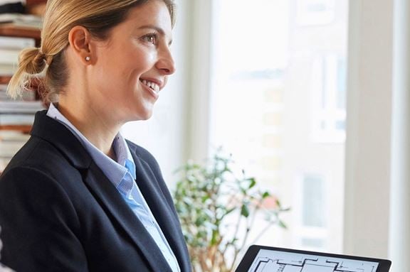 Mäklare som visar en planlösning på en ipad