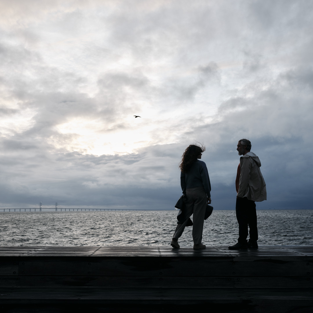 Ett par som står vid havet med Öresundsbron i bakgrunden