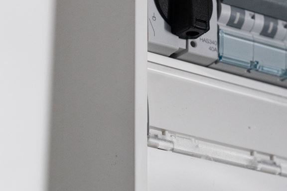 Security elektriker som står vid ett styrskåp och ler