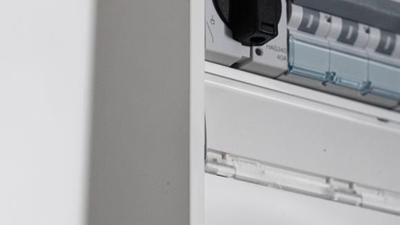 Security elektriker som står vid ett styrskåp och ler
