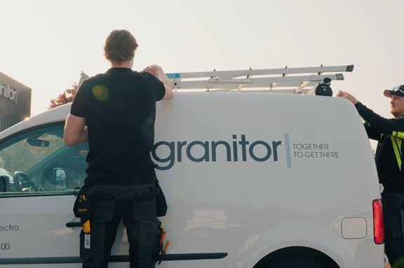 Serviceelektriker står vid bil och plockar av stege från bilens tak