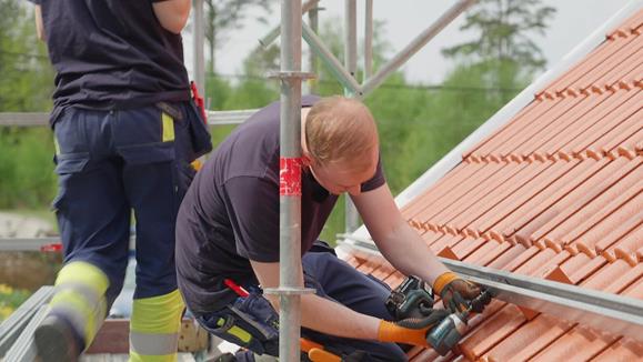Elektriker monterar ställning för solcellspaneler på ett tak.