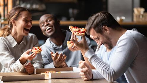 Ett gäng yngre människor äter pizza