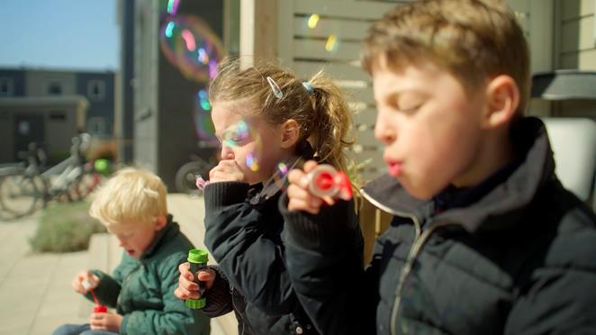 Barn blåser såpbubblor i solen