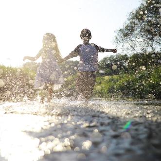 Pojke och flicka som springer i en vattenpöl
