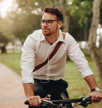 Yngre man med hörlurar som cyklar i en park