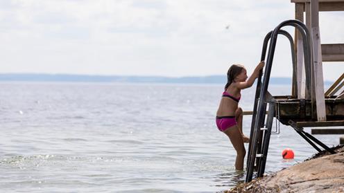 Flicka går ner i vattnet från en brygga