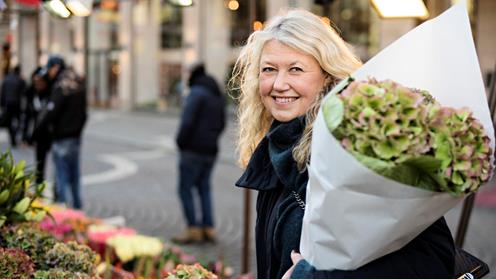 Kvinna på ett torg med en bukett blommor i famnen